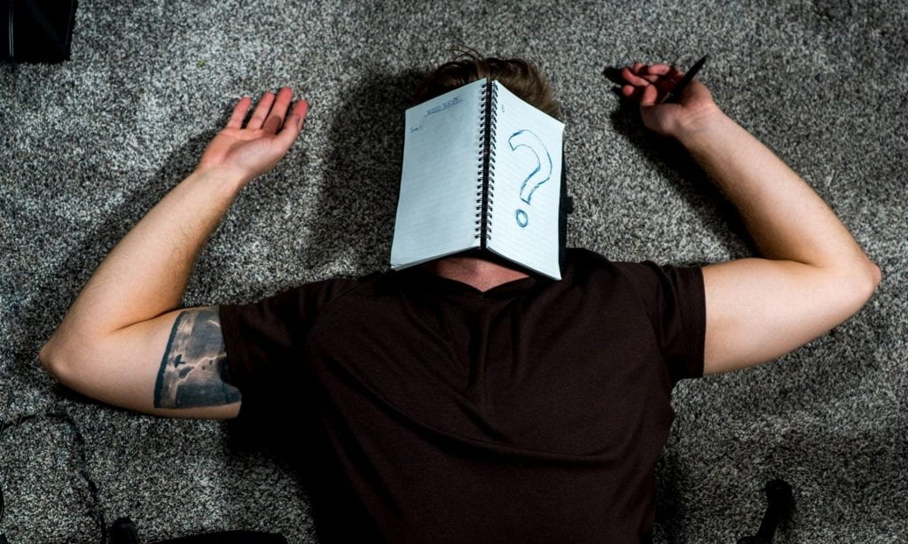 man laying with notebook on his face